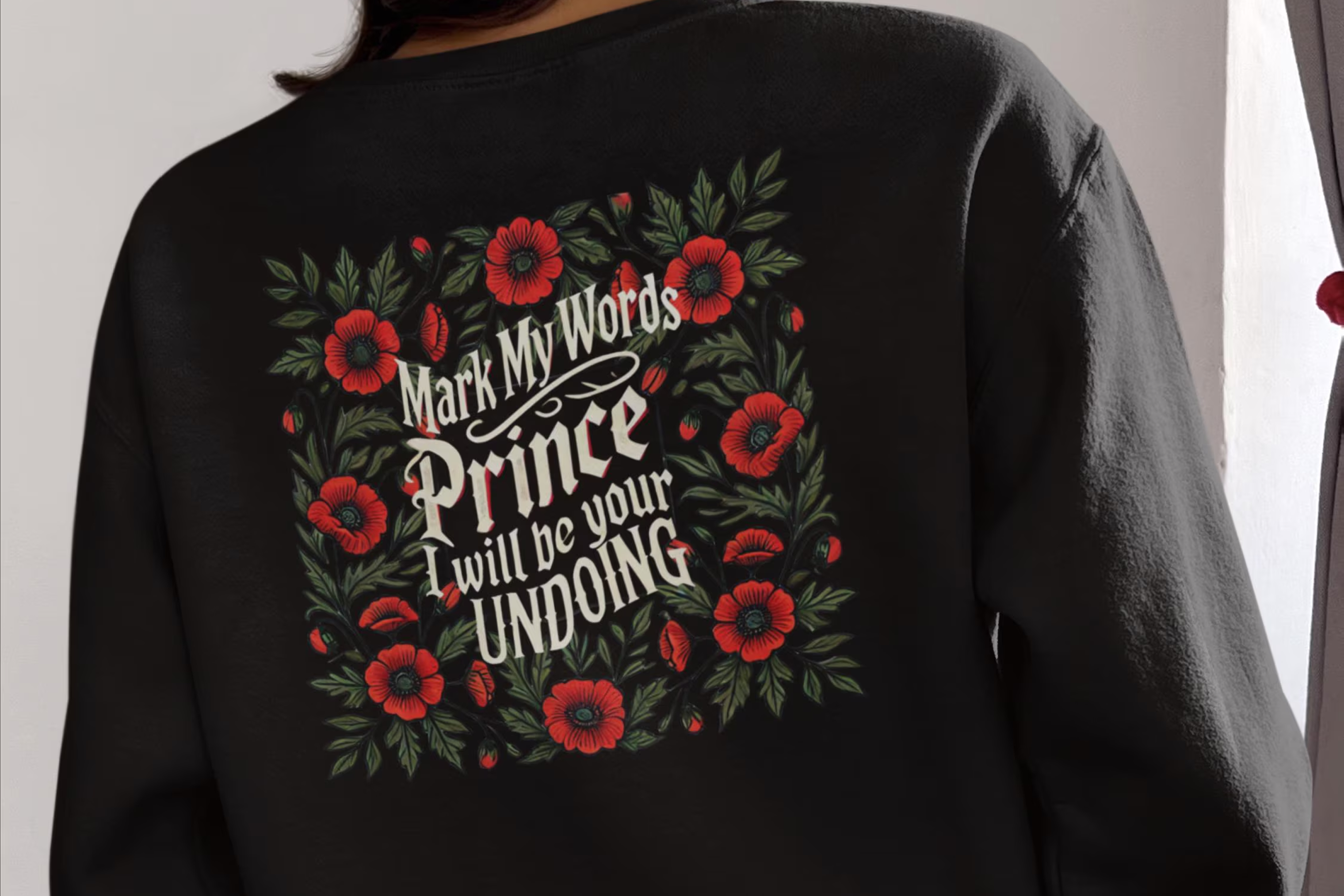 Black sweatshirt with floral design and text on the back, worn by a person.